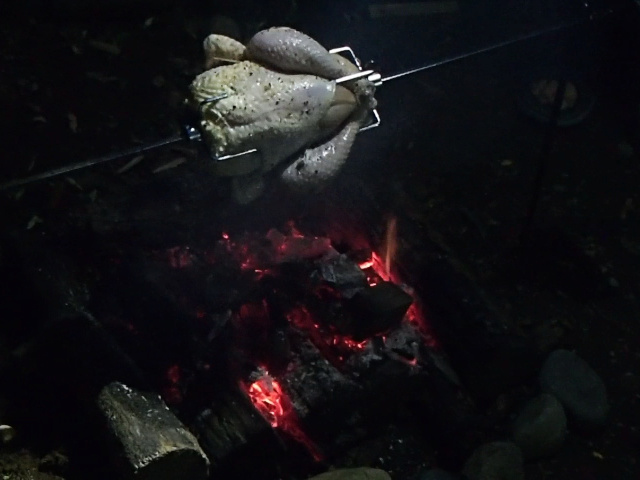 熾火の焚き火上で丸鶏を焼く